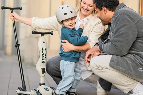 A mother, father and their young son sit next to the Push and Go scooter in the color ash