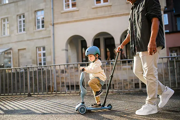 Father pushes his son on the Highwaykick 1 Push and go in blue, the boy is in a standing position