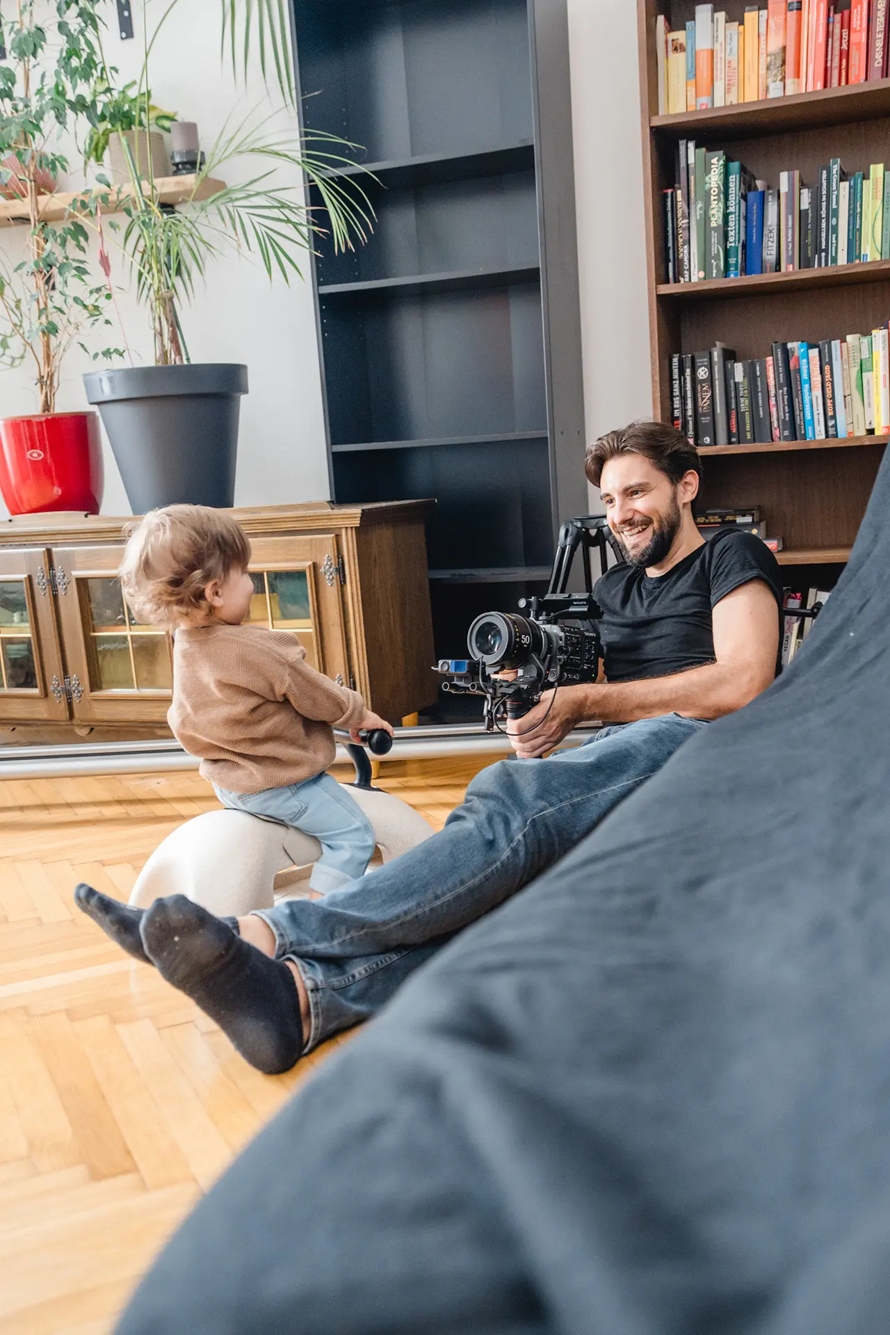Cameraman points camera at little boy, both laugh